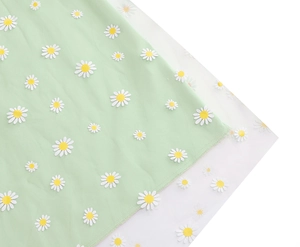 Detail of white daisy embroidery on double-layer mesh and green fabric skirt