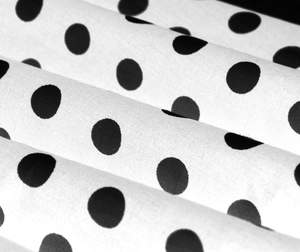 Dettaglio del tessuto in cotone bianco con pois neri classici e trama tessile ben definita