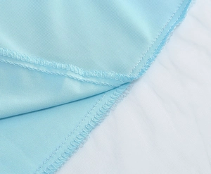 Macro shot showing refined overlock stitching and embroidery detail on light blue fabric