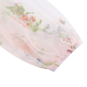 Dettaglio ravvicinato del tessuto in tulle rosa con ricamo floreale sull'orlo dell'abito