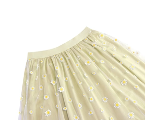 Detail of light green mesh skirt showing delicate white daisy embroidery and elastic waistband