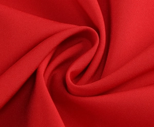 Gros plan sur la texture du tissu satiné rouge avec des plis et drapés élégants
