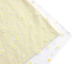 Close-up of yellow floral skirt featuring delicate white daisy embroidery on layered mesh