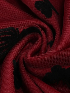 Vista macro del tessuto a rete rosso scuro con motivi floreali a farfalla floccati neri