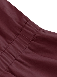 Vista macro dettagliata del tessuto twill rosso vino con pieghe verticali precise e cuciture