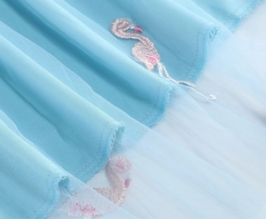 Close-up of pink flamingo embroidery on light blue mesh fabric layer of the skirt