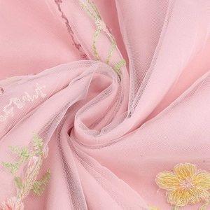 Dettaglio dell'abito in rete rosa chiaro con ricamo floreale e trama del tessuto velato