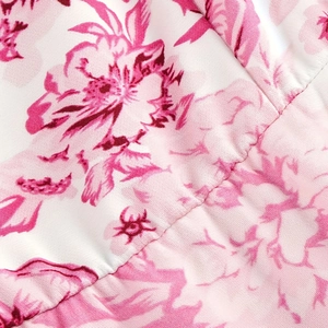 Close-up of floral print fabric with pink blossoms and detailed smocked stitching detail