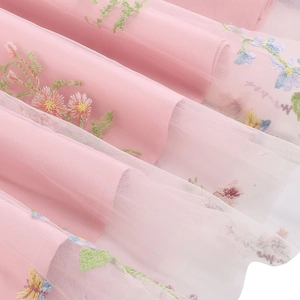 Dettaglio di tessuto a rete rosa con squisito ricamo floreale colorato e strati morbidi
