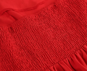 Détail d'une robe en satin rouge avec smocks complexes et texture plissée élastique
