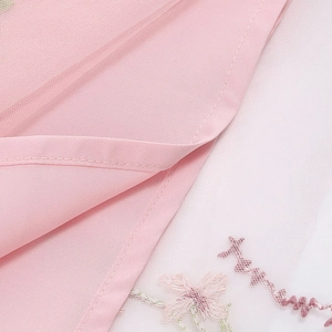 Dettaglio di ricamo floreale rosa su rete traslucida per vestito elegante da bambina