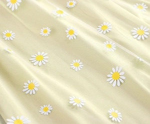 Detailed texture of light green tulle fabric with white daisy embroidery for a summer skirt