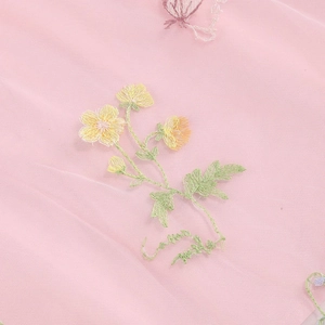 Dettaglio ravvicinato di ricami floreali su tessuto in tulle rosa con trama a rete fine