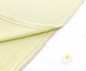 Macro shot of light green woven fabric with daisy embroidery and white lace edges