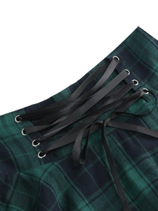 Detail of green plaid skirt featuring black satin laces and silver metal eyelets