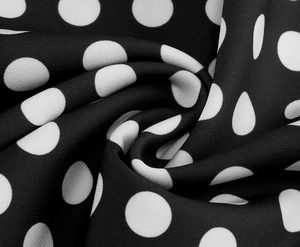 Dettaglio del tessuto vintage a pois neri e bianchi con morbide pieghe drappeggiate