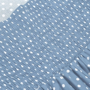 Detailed view of the smocking craft and light blue polka dot fabric with ruffles