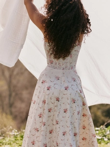 Detail of white floral sundress with pink embroidery patterns in soft natural light