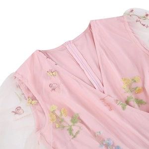 Dettaglio dell'abito ricamato rosa con scollo a V e motivi floreali colorati