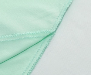 Close-up of overlock stitching and twill texture on a mint green high-waist midi skirt