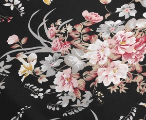 Detail of vintage floral print on black woven fabric with pink roses and lilies