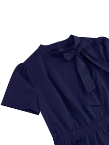 Dettaglio di un abito blu navy a maniche corte con colletto alla coreana, fiocco e maniche a sbuffo