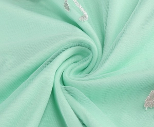 Detailed macro view of mint green tulle fabric with white musical note embroidery patterns