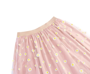 Detail of pink mesh skirt featuring intricate white daisy embroidery and elastic waistband