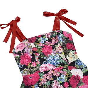 Dettaglio delle spalline con fiocco in raso rosso su abito vintage a fiori