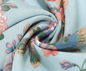 Close-up of light blue floral printed fabric with smooth texture and soft drape detail