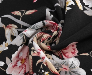 Close-up of vintage tropical floral print fabric with pink flowers on black background