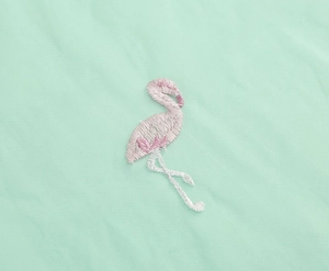 Detail of pink flamingo embroidery on mint green high-waisted skirt fabric