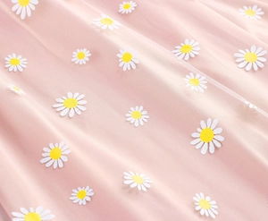 Macro detail of embroidered daisies on pink tulle mesh fabric with delicate textures