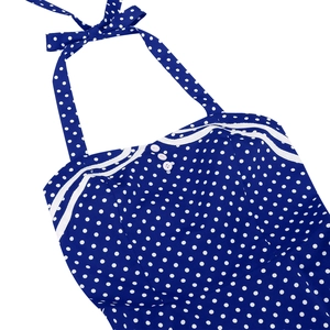 Detail of navy blue polka dot dress featuring halter neck tie and white button decor