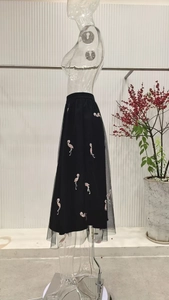 Detailed embroidery of pink flamingos on a layered black mesh midi skirt with elastic waist