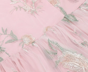 Detailed embroidery of pink floral patterns on sheer tulle fabric for vintage gown