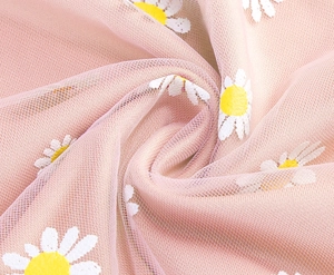 Detailed macro view of pink tulle mesh fabric with delicate daisy floral embroidery