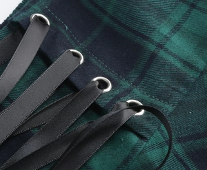 Close-up of green plaid skirt fabric featuring metal eyelets and black satin ribbon ties