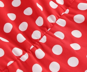 Détail macro d'une robe rouge à pois avec fronces élastiques et coutures précises