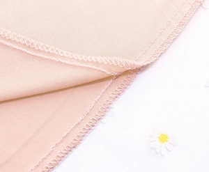 Detailed macro view of daisy lace embroidery on high waist pink mesh skirt hemline