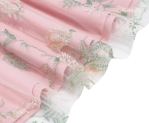 Detailed macro view of pink floral embroidery on semi-transparent mesh fabric of dress