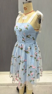 Detail of light blue mesh dress featuring delicate floral embroidery and white ribbon straps