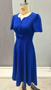 Detail of a blue V-neck dress featuring a waist bow and flowing A-line skirt texture