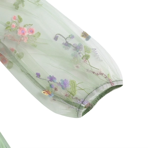 Dettaglio di ricamo floreale su manica in mesh verde chiaro con polsino elastico