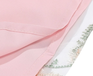 Close-up of pink dress hem with floral embroidery and white mesh lace layering