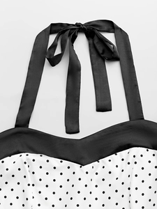 Détail de robe à pois avec nœud de cou en satin noir et décolleté en forme de cœur