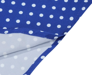 Détail macro du tissu à pois bleus montrant la couture de l'ourlet et la qualité de finition