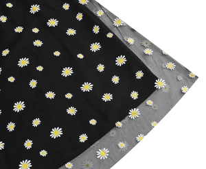 Detailed close-up of daisy print on layered black mesh fabric and inner lining
