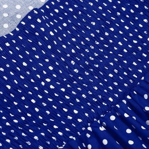 Close-up of smocking texture on royal blue polka dot cotton dress with elasticated details