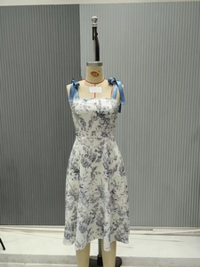 Dettaglio delle spalline in nastro blu con fiocchi su un abito estivo a fiori bianco